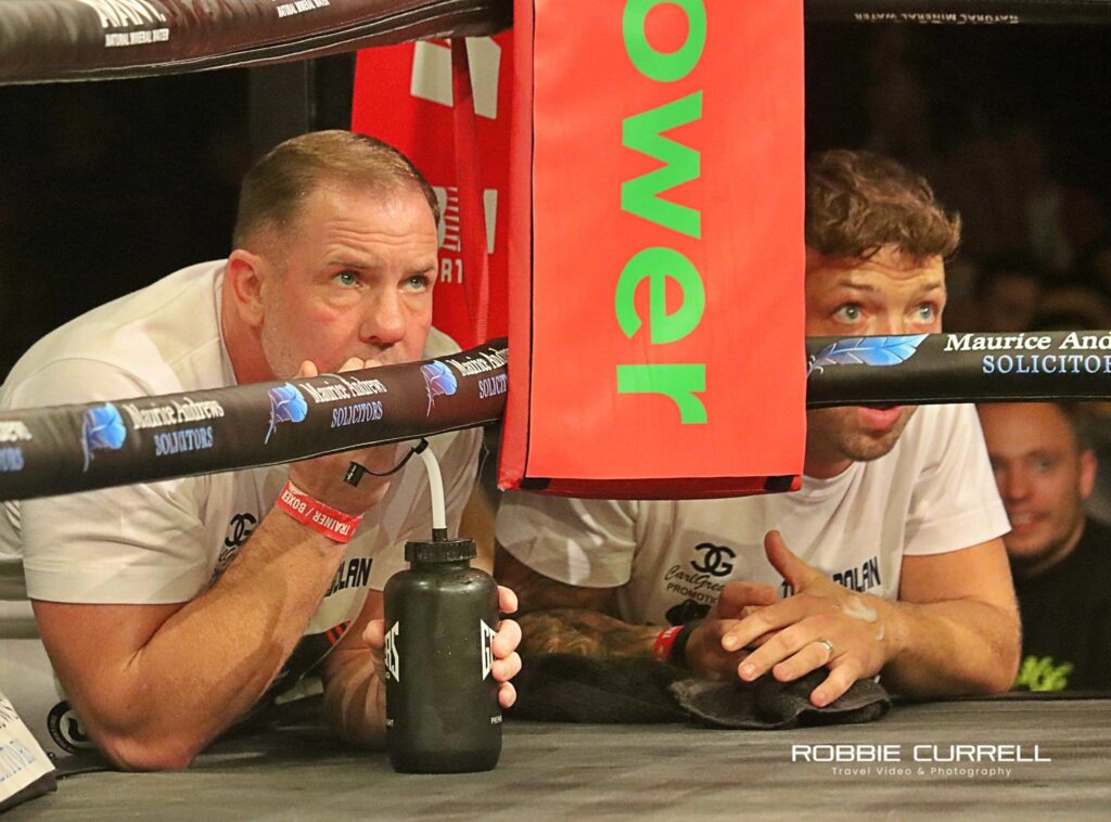 Carl Greaves (on the left) leans on the ring as he watches one of his fighters in a boxing match