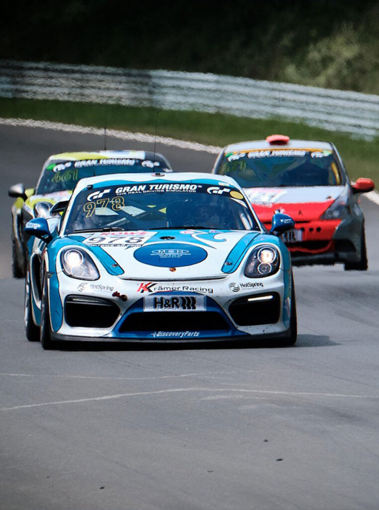 White and blue race car on track in front of two other cars