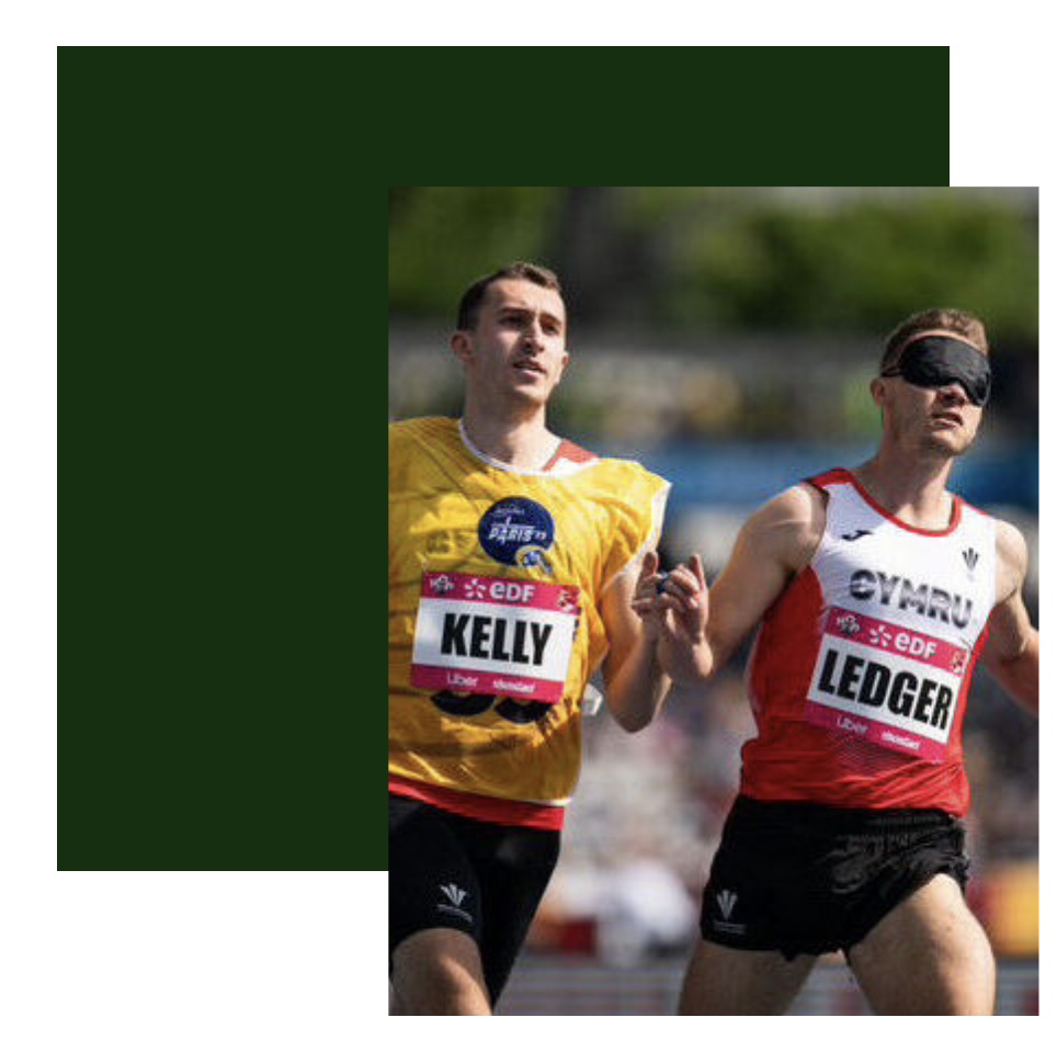 Great Britain's 100 metre blind sprint record holders James Ledger, wearing a red and white running vest, and guide runner Greg Kelly, wearing a yellow vest are attached a 6cm running cord as they approach the finish line.