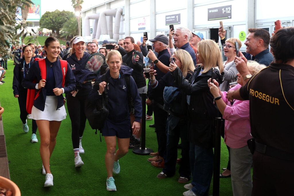 Emma Raducanu and Katie Boulter walk just infront of Milena Mirkovic (physio) and her team, whilst fans are clapping either side of them as they approach the Billie Jean King Cup competition.