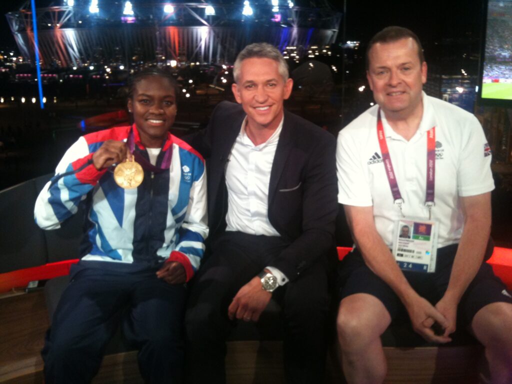 Nicola Adams (left) holding her gold medal from the Boxing at the 2012 Olympics sat next to pundit Gary Lineker, and Richard Prescott (right) in the BBC's Tv studio
