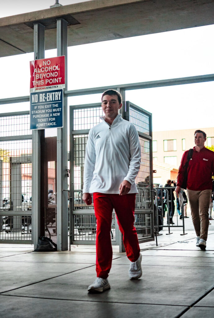 Patrick Reaves walks into a stadium wearing a white tracksuit top and red tracksuit.