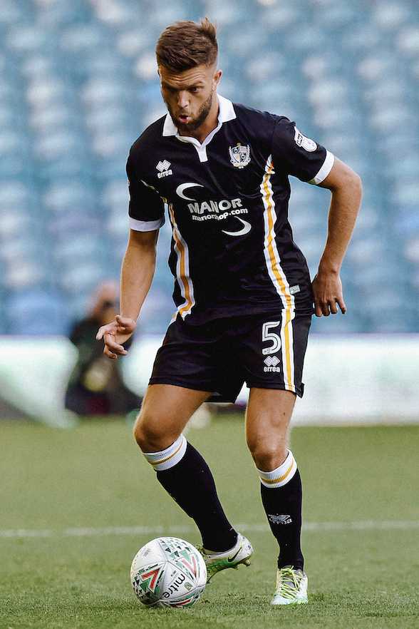 Ex-professional footballer Joe Davis, dons a full black Port Vale strip whilst receiving the ball on his right foot.
