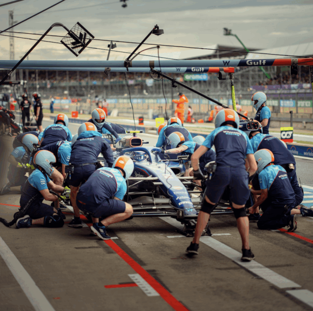 A car in pit stop with crew gathered around it.