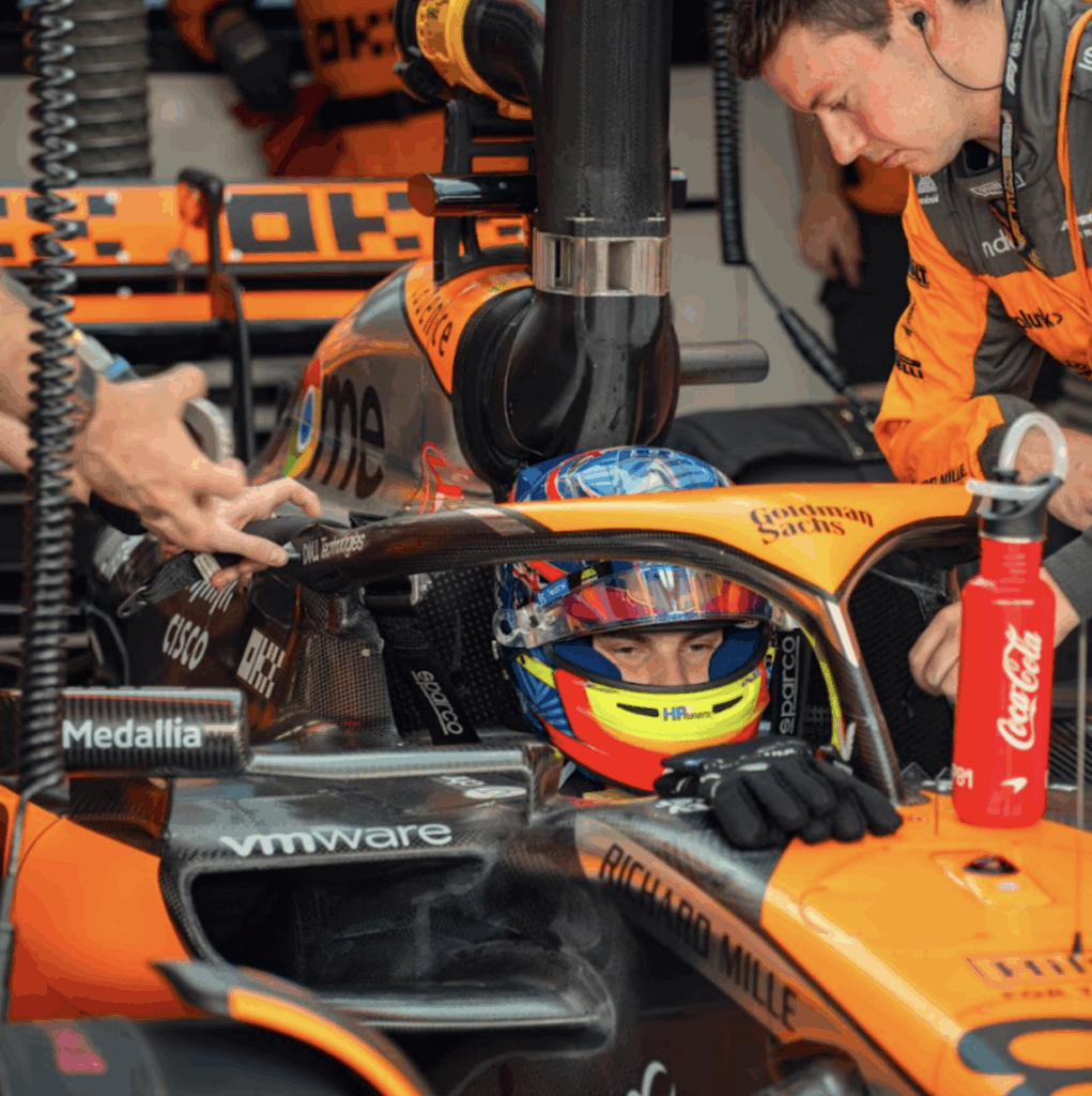 A driver sat in the seat of an orange F1 car.