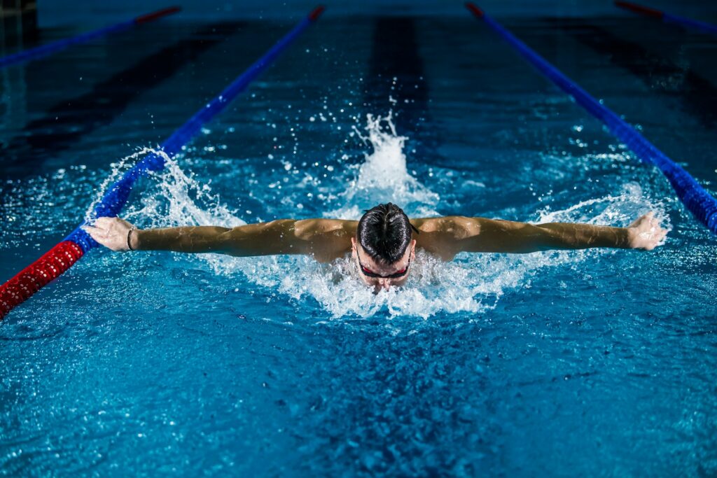 An image of a man mid-stroke swimming butterfly down a pool towards the camera.