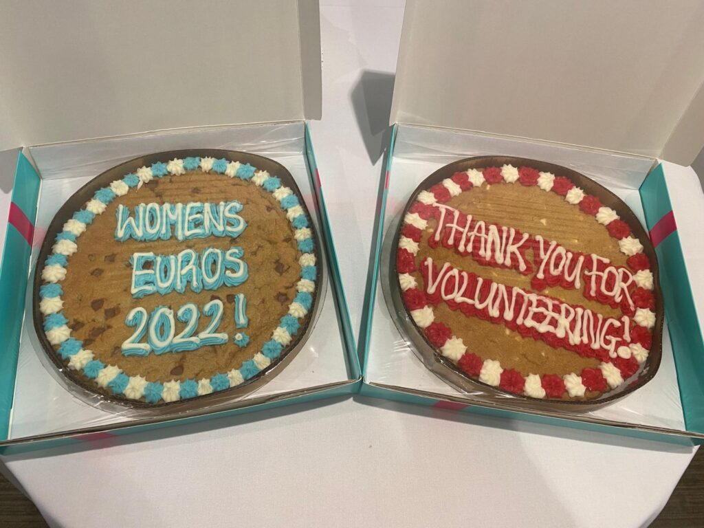 shows two cakes side by side one labelled 'Women's Euros 2022!' and the other labelled 'Thank you for volunteering!'